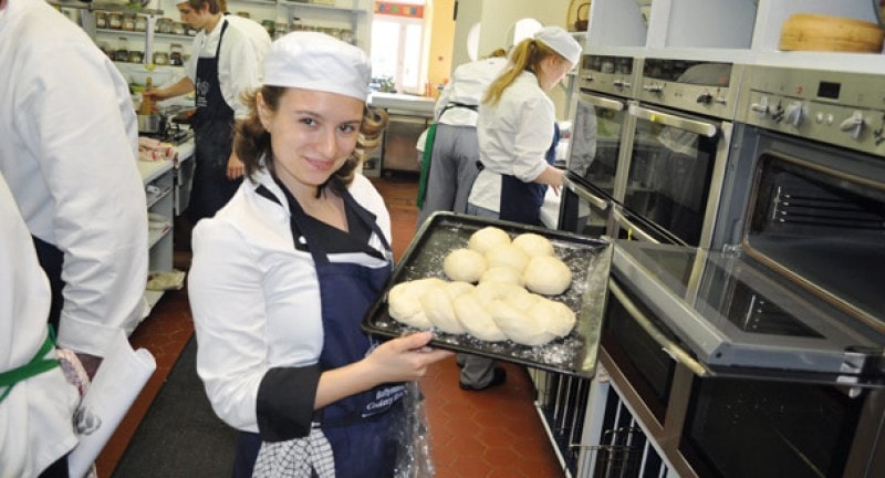 Girl placing bread into an oven