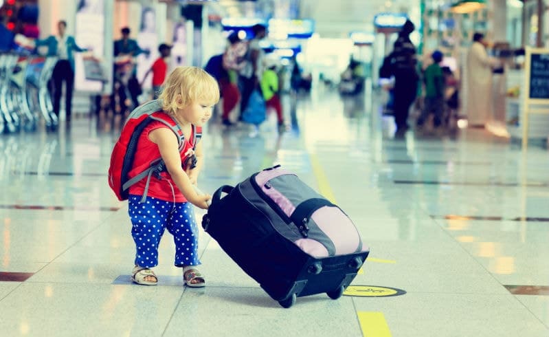 Little girl in the airport holding suitcase