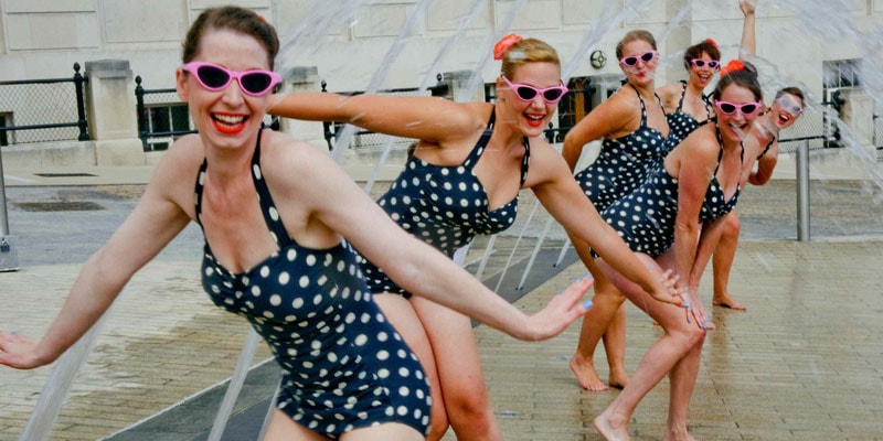 women in polka dot swimming costumes in urban fountain