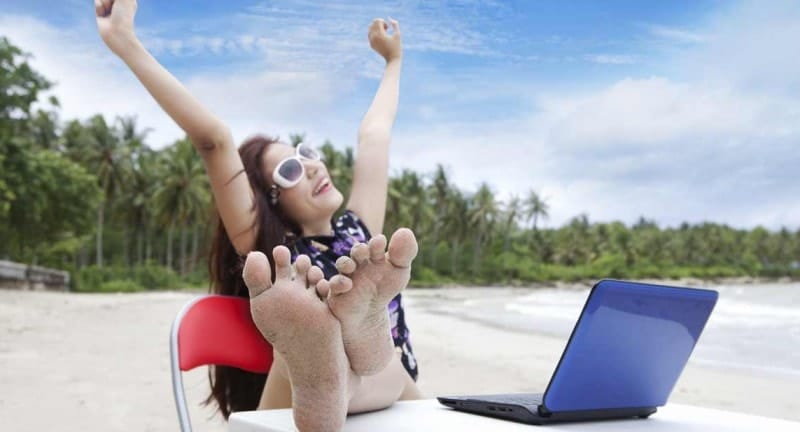 woman with laptop on beach celebrates