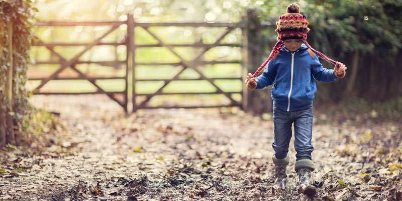 little-boy-in-wellies-walking-in-woods-in-autumn