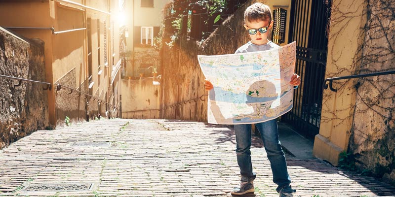 little-boy-looking-at-map-on-old-street-in-itlay