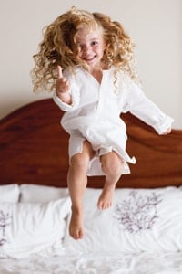 little-girl-jumping-on-bed-at-hotel-at-beaches-resort