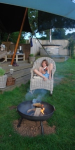 A small boy sits in a whicker chair infront of a firepit at Dandelion Hideaway