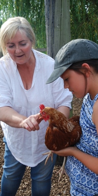 A lady shows a girl a hen at Dandelion Hideaway