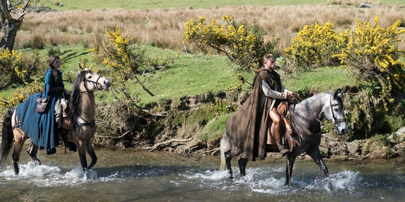 A still from King Arthur: Legend of the Sword in Gwyant, Snowdonia with a man and a woman on horseback in the river