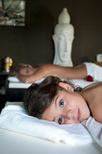 A girl and mother lying on side by side massage beds in spa