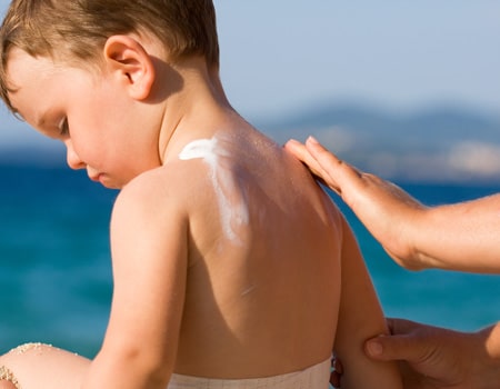 applying sunscreen on boy sun safe