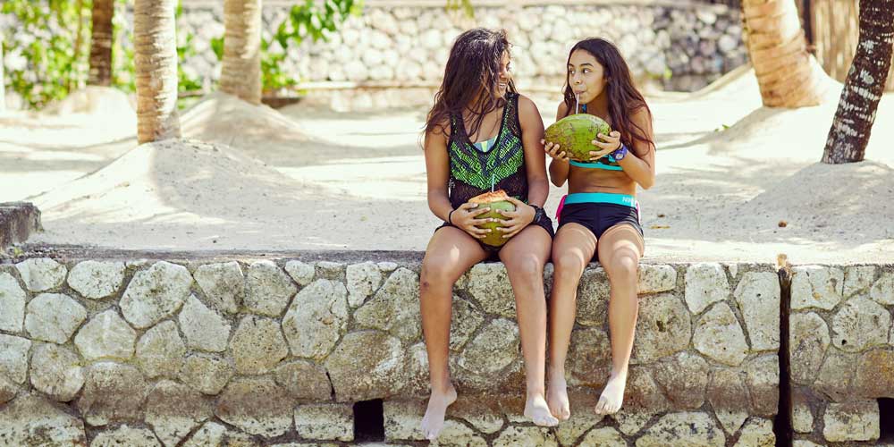 Girls drinking from coconuts summer savings