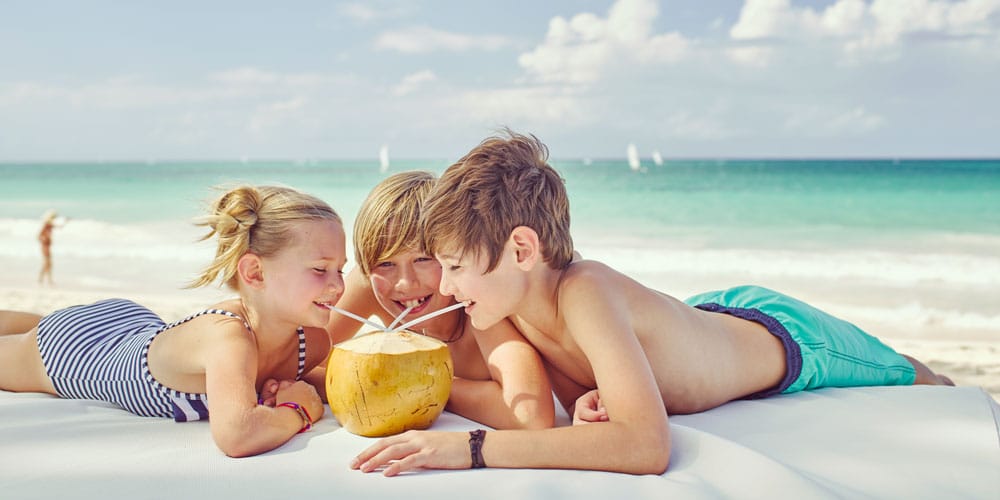 Beach kids drinking from coconut summer savings