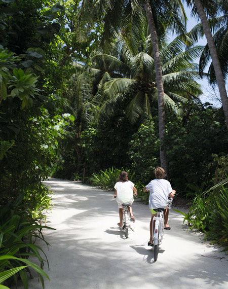 Kids cycling through trees Maldives