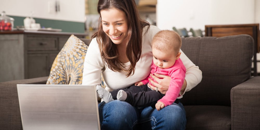 mother checking weather online with baby - tips for your first holiday with a baby