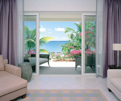 The spectacular view from a Beach Terrace Suite including palm trees, pink flowers and the sea in the background