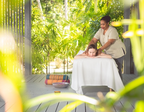 A masseuse massages a women outdoors at Carlisle Bay spa