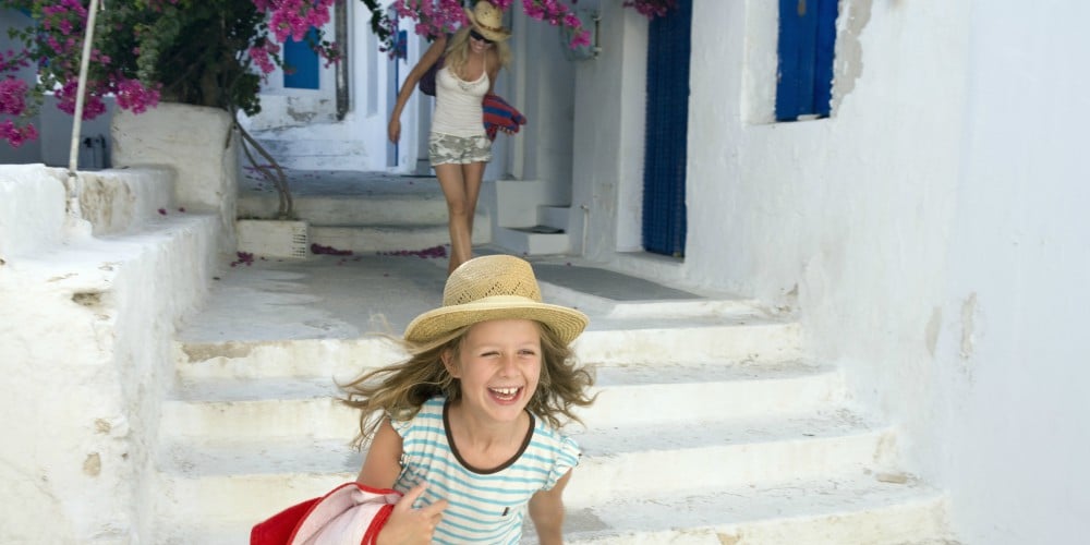 best family holiday destinations 2019, girl runs through Greek island village