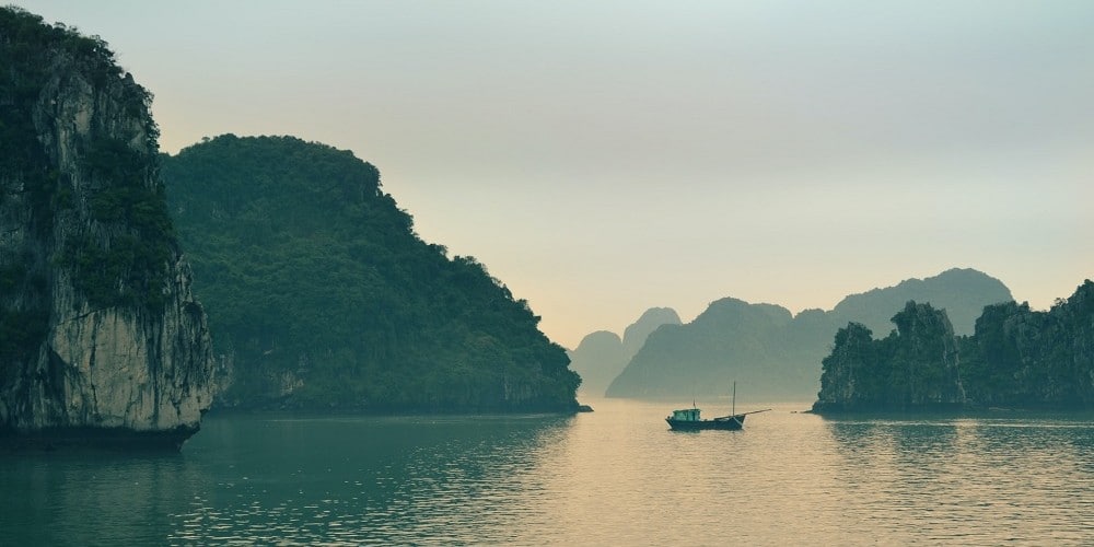 Hu Long Bay Vietnam limestone karsts and junk at dawn