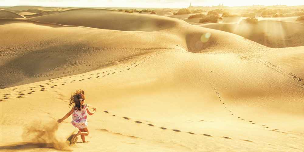 canary-islands-guide-young-child-running-across-maspalomas-dunes-gran-canaria