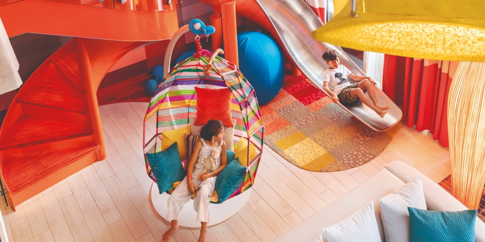 family-suite-best-family-cruise-holidays-kid-on-bedroom-slide-girl-in-hanging-chair-royal-caribbean