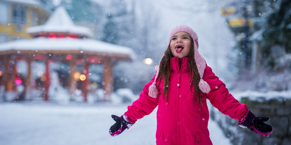 whistler-village-little-girl-in-ski-gear-tasting-snow-start-of-a-family-ski-day