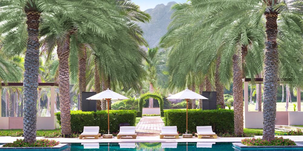 al-bustan-palace-hotel-pool-oasis-gardens-mountain-backdrop-muscat-oman 