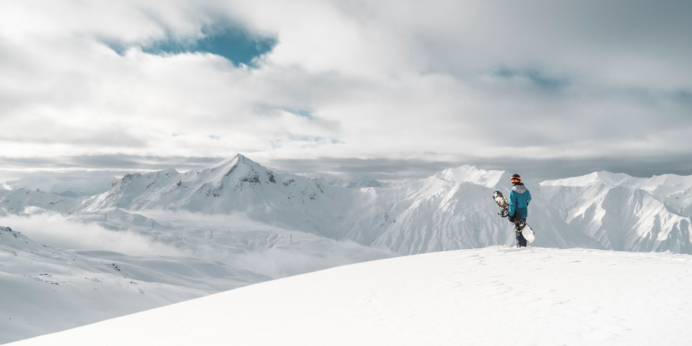 les-menuires-savoie-france-yann-allegre-snowboarder-on-summit-staring-over-snowy-mountain-tops 