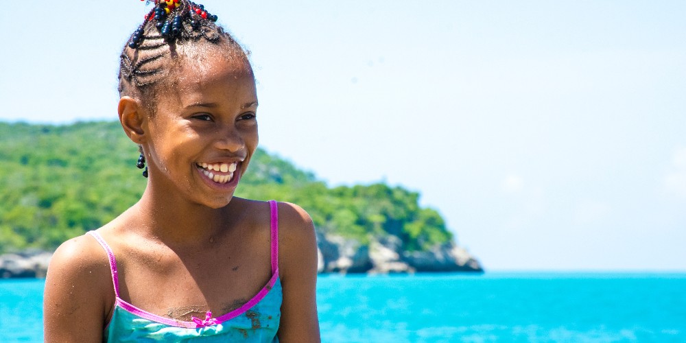 little-girl-big-wide-smile-against-blue-sea-treasure-beach-jamaica-oshin-wong 