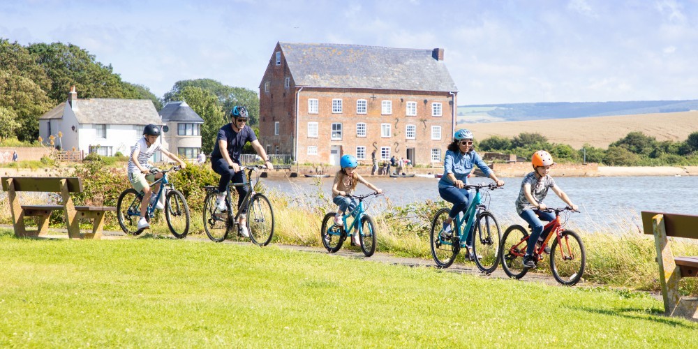 family-of-five-cycling-by-a-lake-with-sailing-boats-spring-day-wightlink-ferries