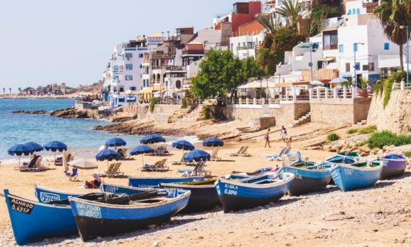 taghazout-morocco-blue-boats-on-a-sunny-beach-with-white-houses-and-blue-sun-umbrellas-louis-hansel