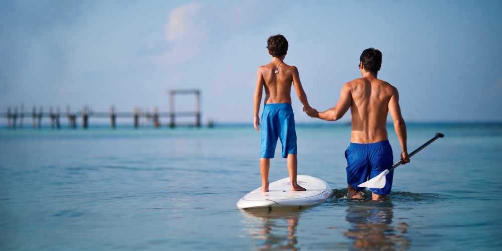 father-and-son-paddleboarding-in-caribbean-seas-nizuc-resort-family-holidays-in-cancun