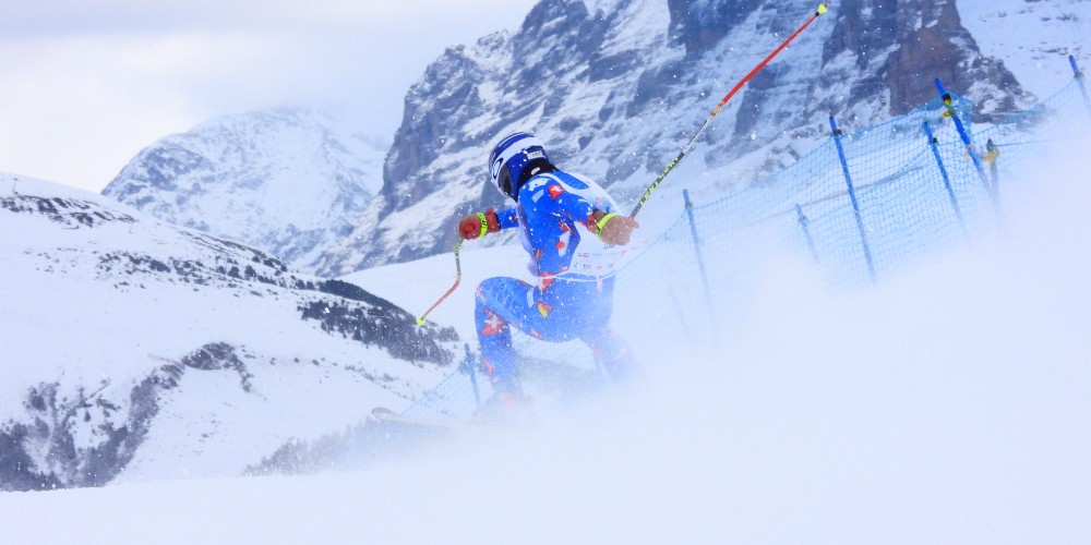 murren-switzerland-inferno-ski-race-2022-racer-carving-deep-snow-against-mountain-backdrop-family-traveller