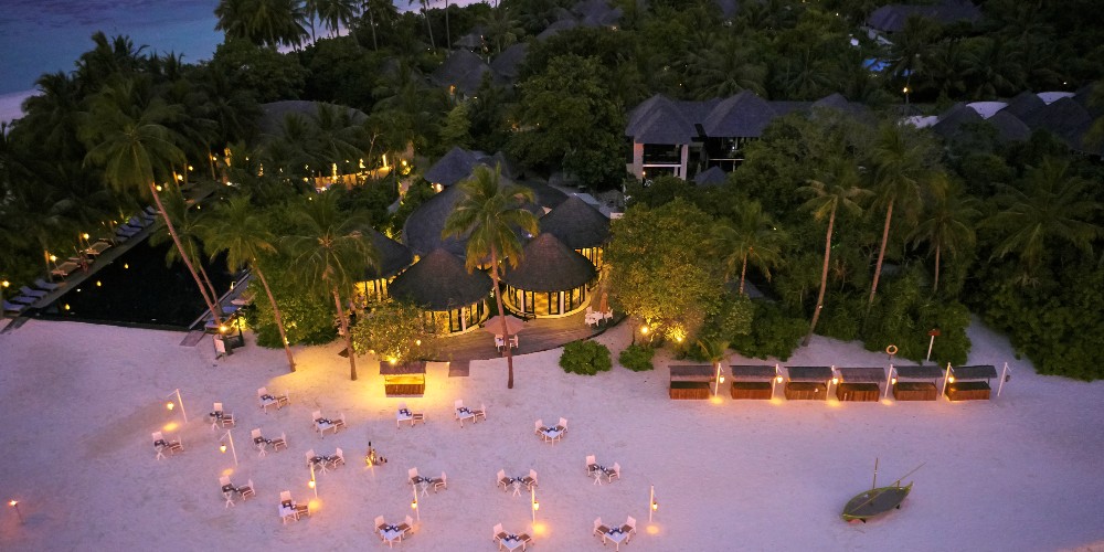 sun-siyam-iru-fushi-resort-evening-restaurant-tables-on-lamplit-white-sand-beach-maldives-family-holidays-2022