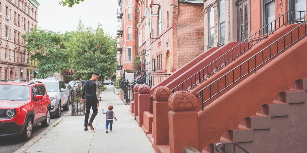 father-and-child-walking-in-front-of-brownstones-harlem-new-york-for-families-2022
