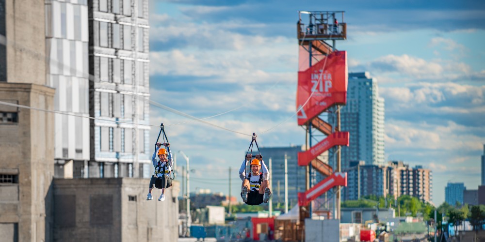 two-adults-ziplining-from-ontario-to-quebec-on-interzip-rogers-summer-breaks-in-ottawa-2022 
