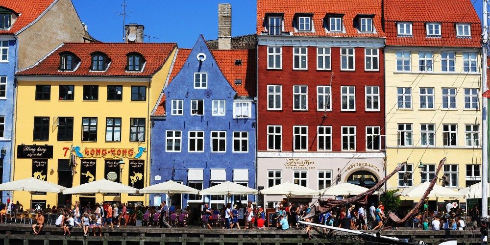 nyhavn-copenhagen-colourful-houses-waterfront-tourists-sunbathing-ambassador-cruise-line-nordic-treasure-cruises-2022