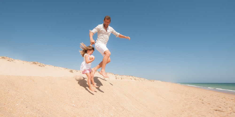 father-daughter-jumping-sand-dune-quinto-do-lago-beach
