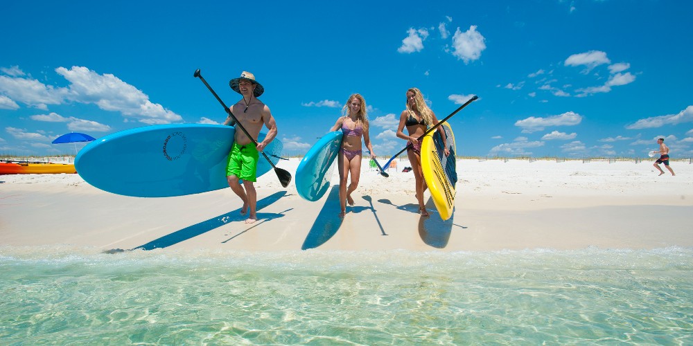 young-adults-paddleboarding-gulf-coast-beach