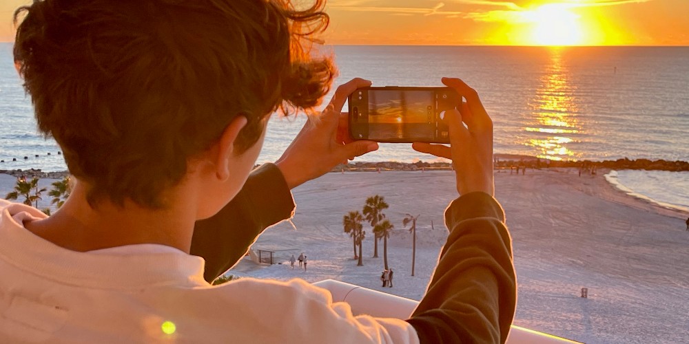 boy-taking-phone-picture-of-sunset