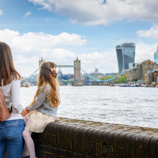 A mother and daughter on a sightseeing city trip looking at the skyline of London, England, with river Thames and Tower Bridge