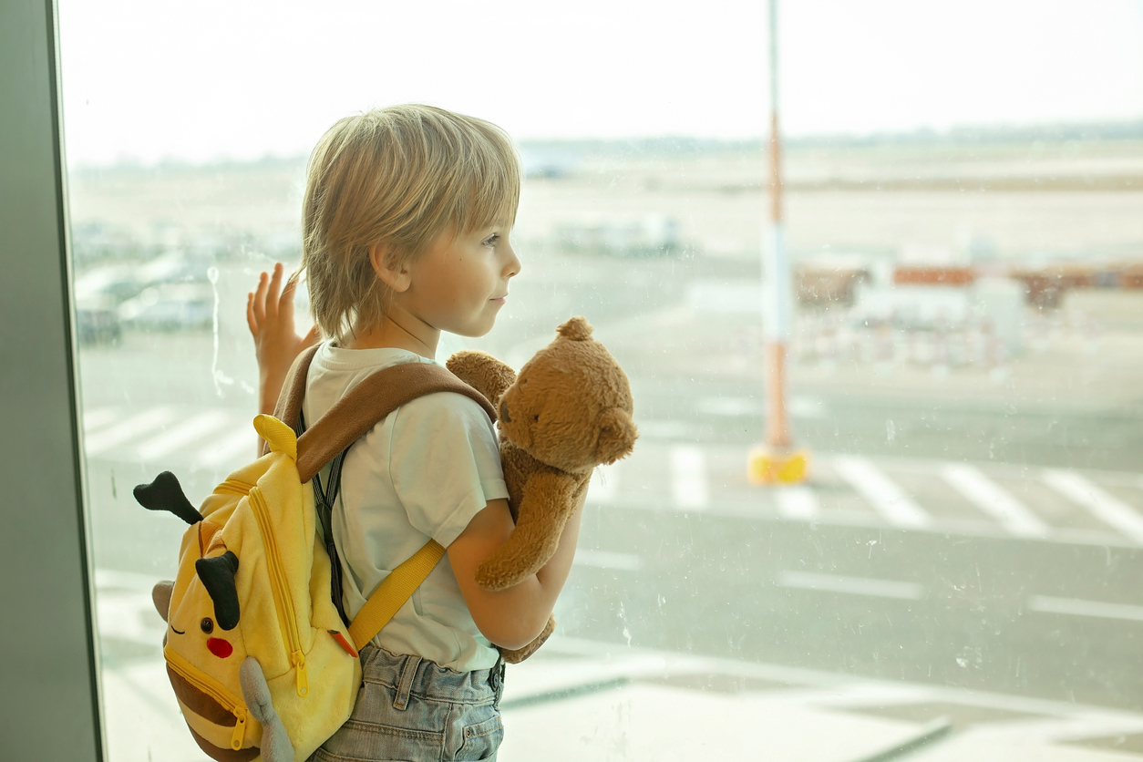 Child, watching from the window of the airport the planes, taking off and landing while waiting at to board the aircraft