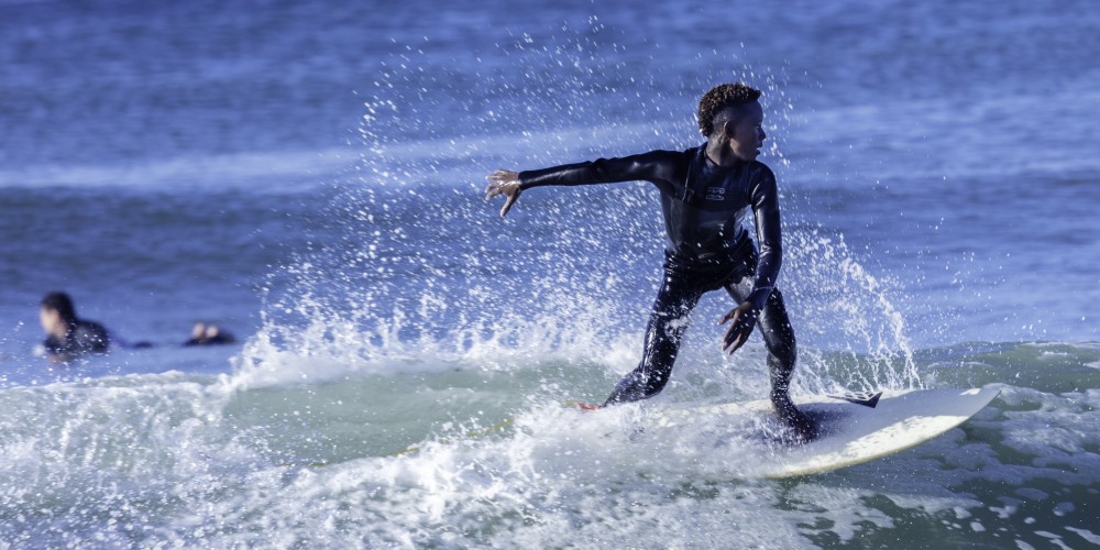 boy-in-full-wetsuit-surfing-california