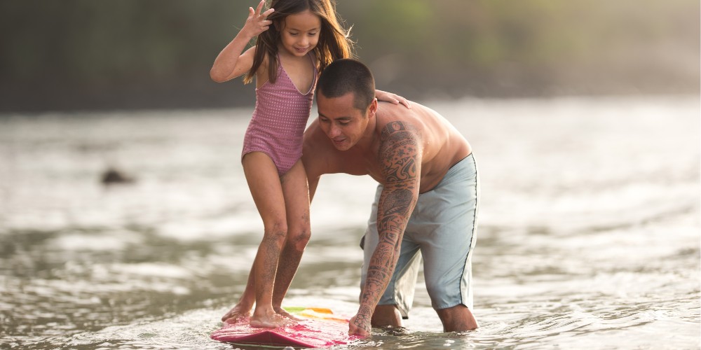 young-dad-teaching-daughter-to surf