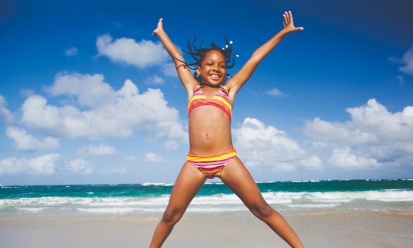 caribbean-island-holidays-young-girl-doing-star-jumps-in-stripey-bikini-on-caribbean-beach