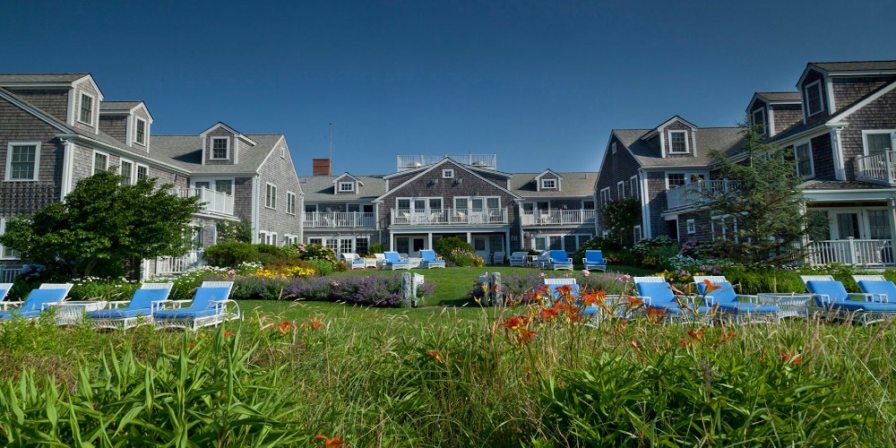 white-elephant-hotel-nantucket-exterior-summer-garden-with-blue-skies-and-blue-sun-beds-family-traveller-2022