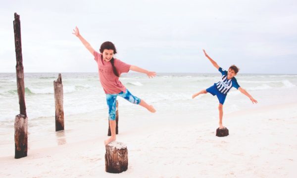 fun-florida-family-vacations-kids-balancing-on-rocks-pensacola-beach-2022