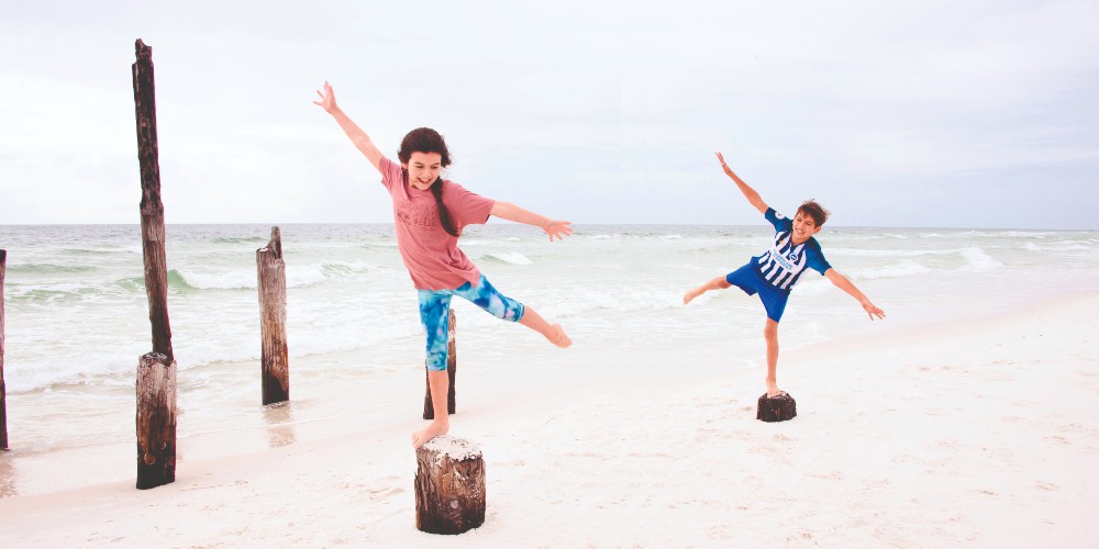fun-florida-family-vacations-kids-balancing-on-rocks-pensacola-beach-2022