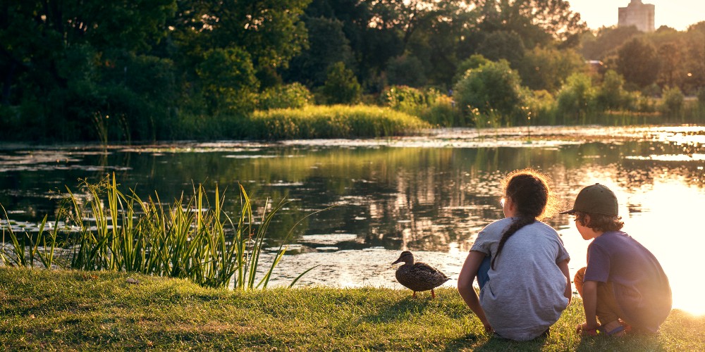 two-children-feeding-ducks-at-sunset-by-a-pond-family-activities-montreal-summer-2022