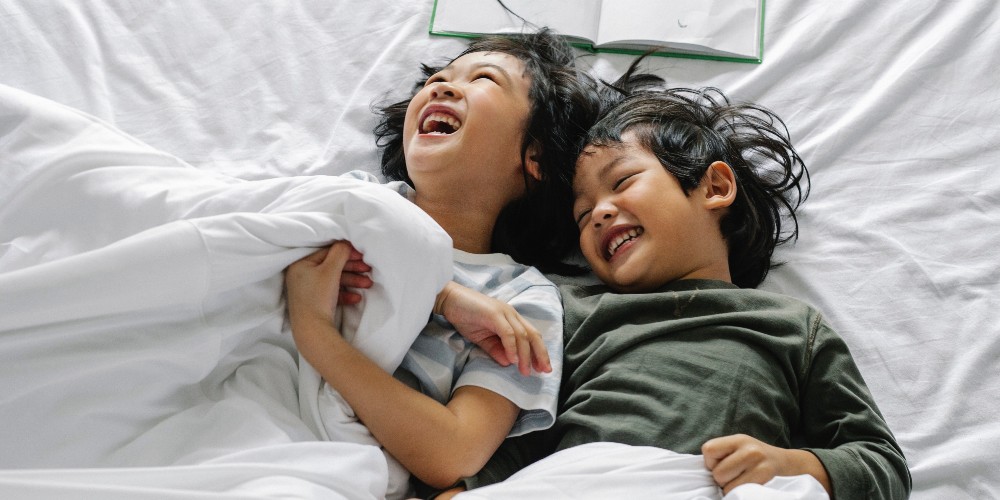 children-laughing-in-white-hotel-bed-pexels-alex-green