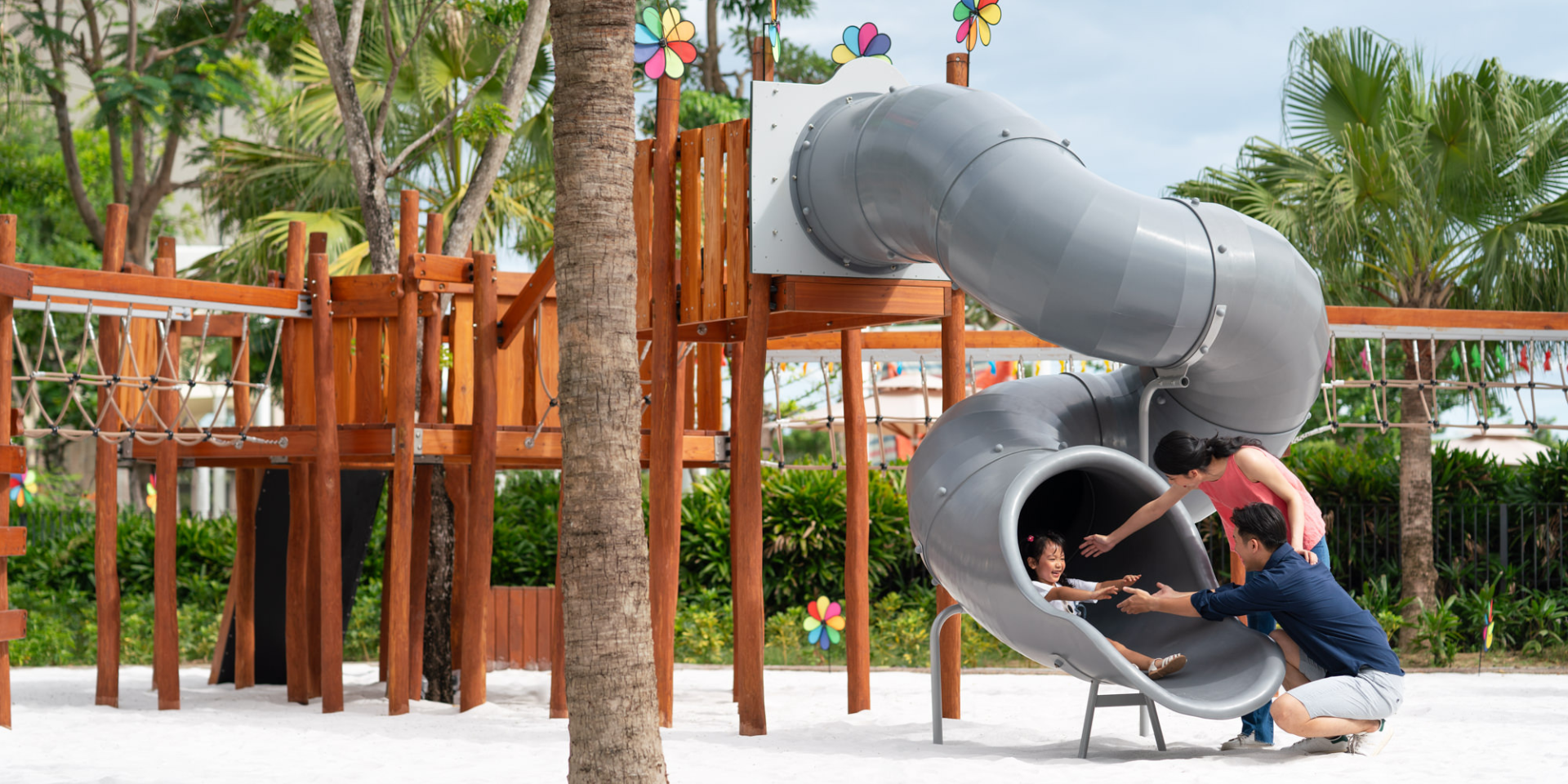 playground with grey slides. young girl sliding into parents' arms
