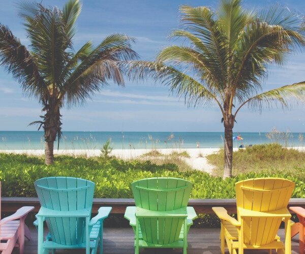 florida-family-holidays-anna-maria-island-colourful-adirondak-chairs-facing-palm-tree-lined-gulf-coast-beach