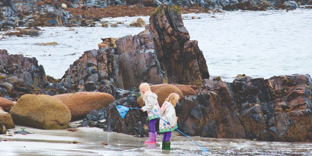 little-girls-rockpooling-with-fishing-nets-rocky-beach-iona-Hebridean-island-breaks-family-traveller